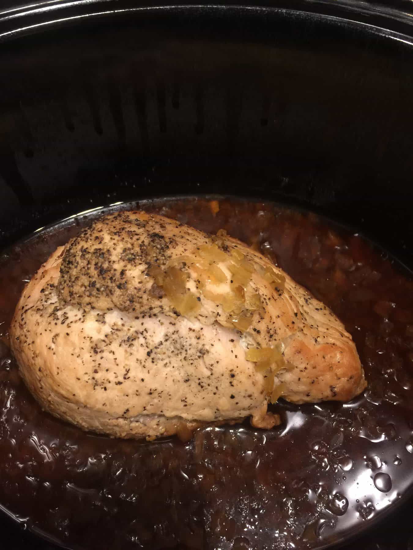 Picture of cooked pork roast and onions with root beer in a slow cooker.