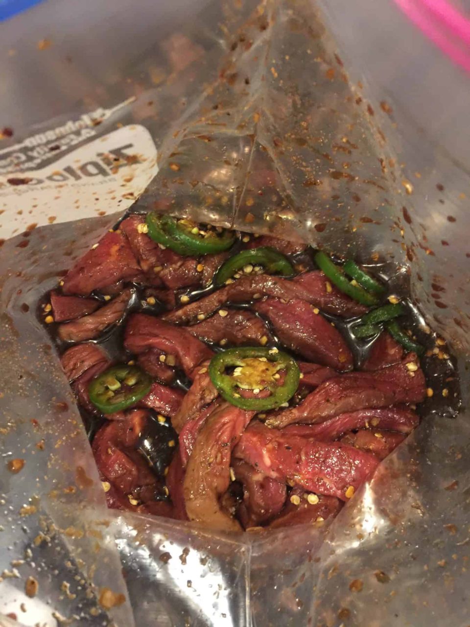 Meat & marinade in a zip top bag with jalapeno peppers for Sweet & Spicy Beef Jerky.