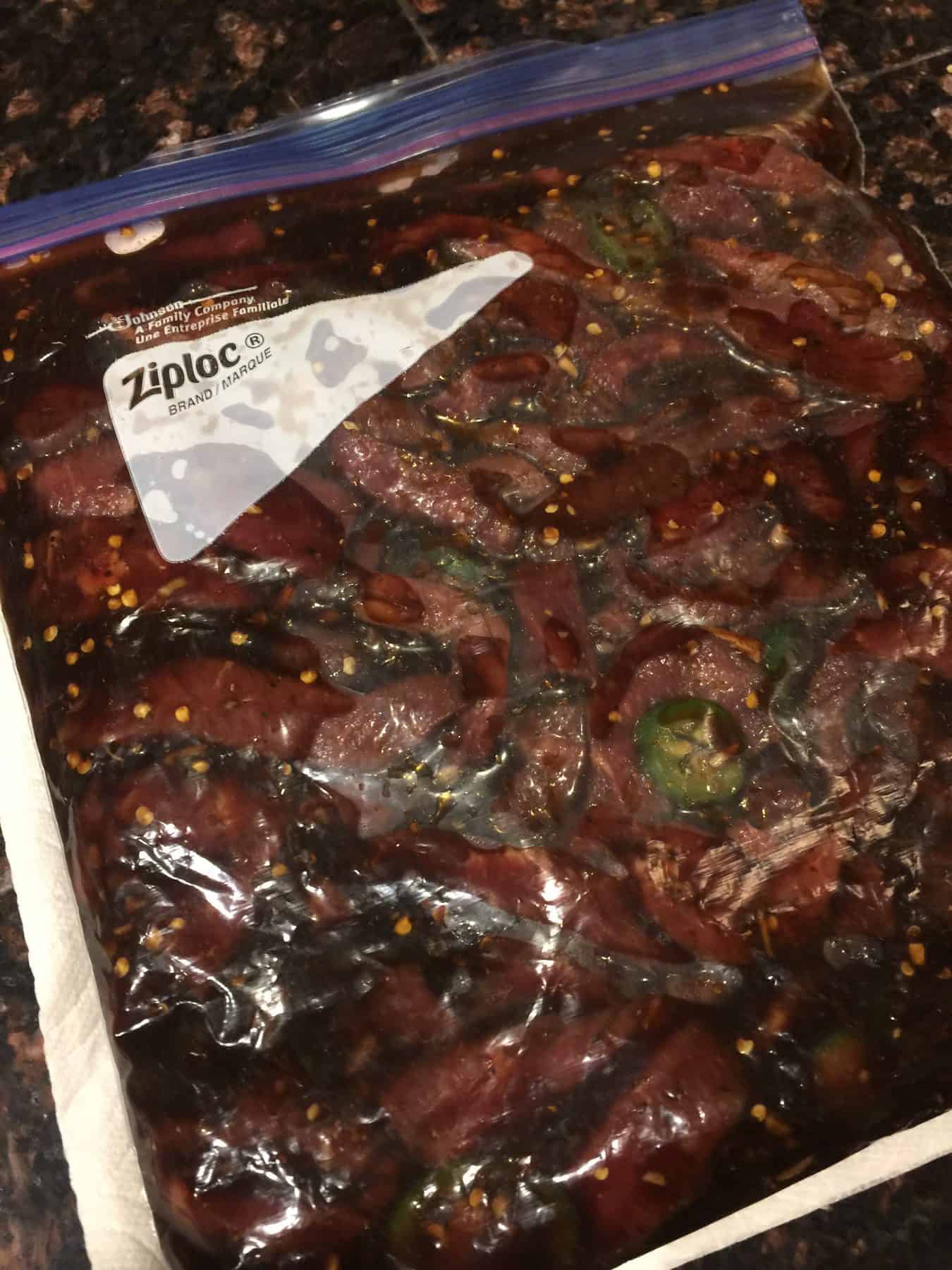Sealed zip top bag of meat in the marinade for Sweet & Spicy Beef Jerky.
