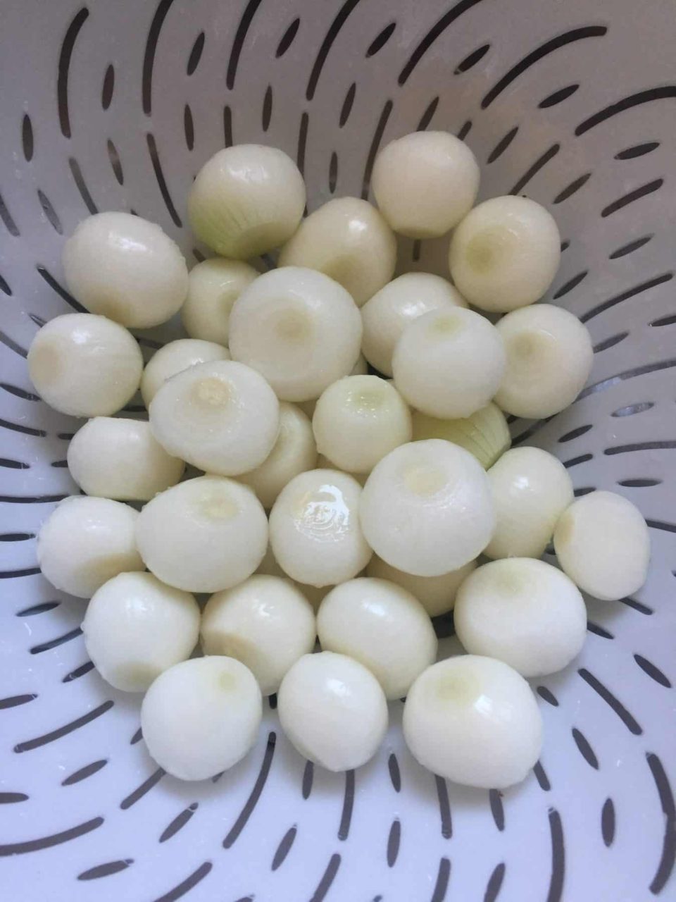 Picture of cleaned and peeled onions in a colander.