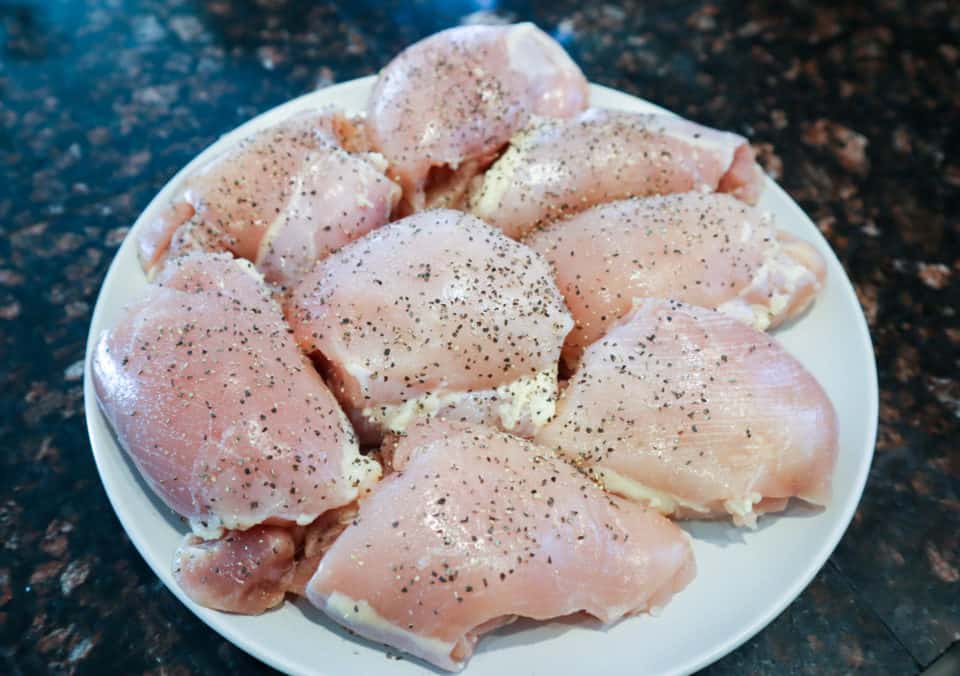 Chicken thighs on a plate seasoned with salt & pepper.