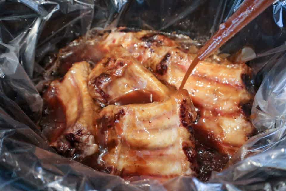 Picture of ribs being basted with sauce for Slow Cooker Sweet & Sour Ribs