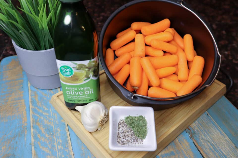 Ingredients for Air Fryer Roasted Baby Carrots on a board.