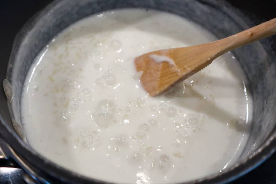 Process shot of rice, salt, sugar and milk cooking in a heavy pot for Classic Rice Pudding