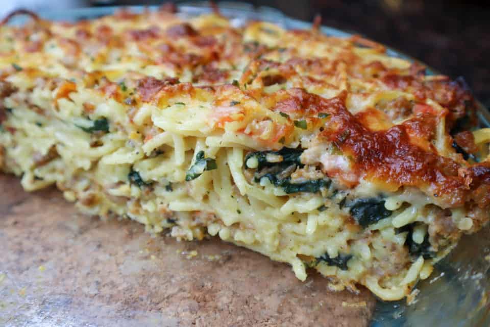 Close up picture of baked Spinach and Sausage Spaghetti Pie in a pie plate.