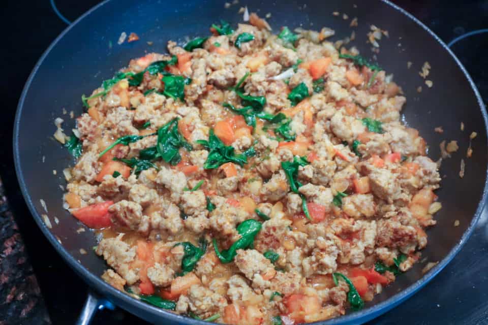 Picture of sausage, spinach, tomatoes and onions in skillet for Spinach and Sausage Spaghetti Pie.