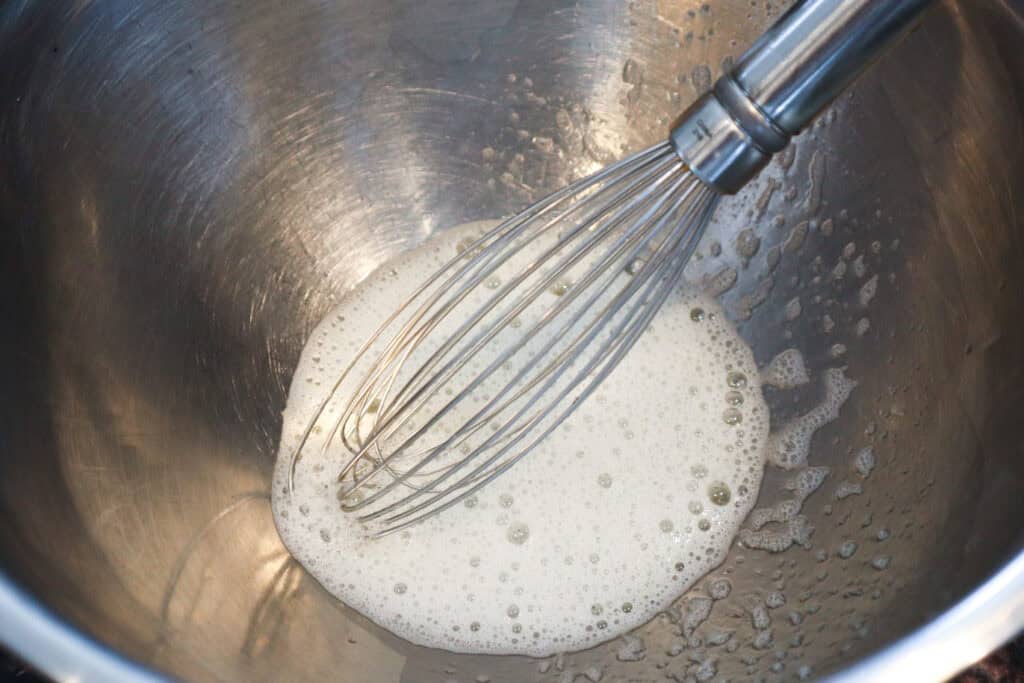 Frothy egg whites pictured with a whisk.