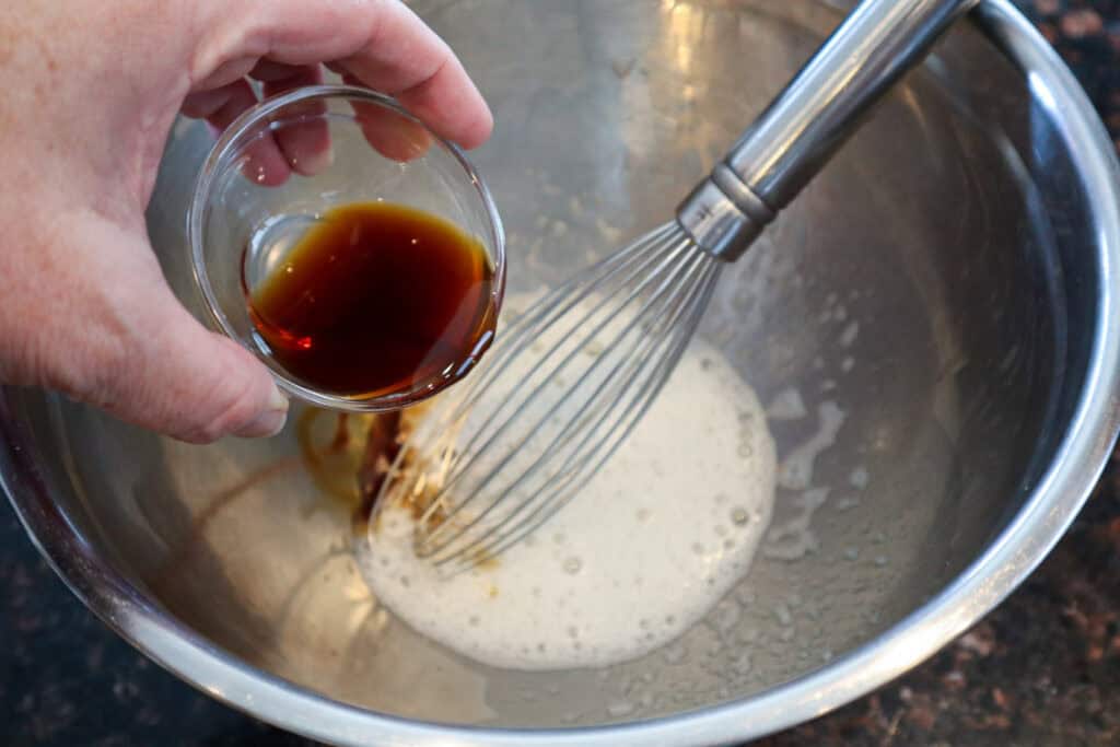 Adding vanilla extract to the frothy egg whites.