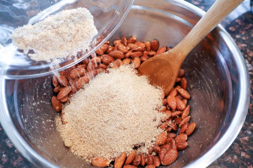 Tossing the prepared almonds in the sugar mixture prior to roasting in the oven.