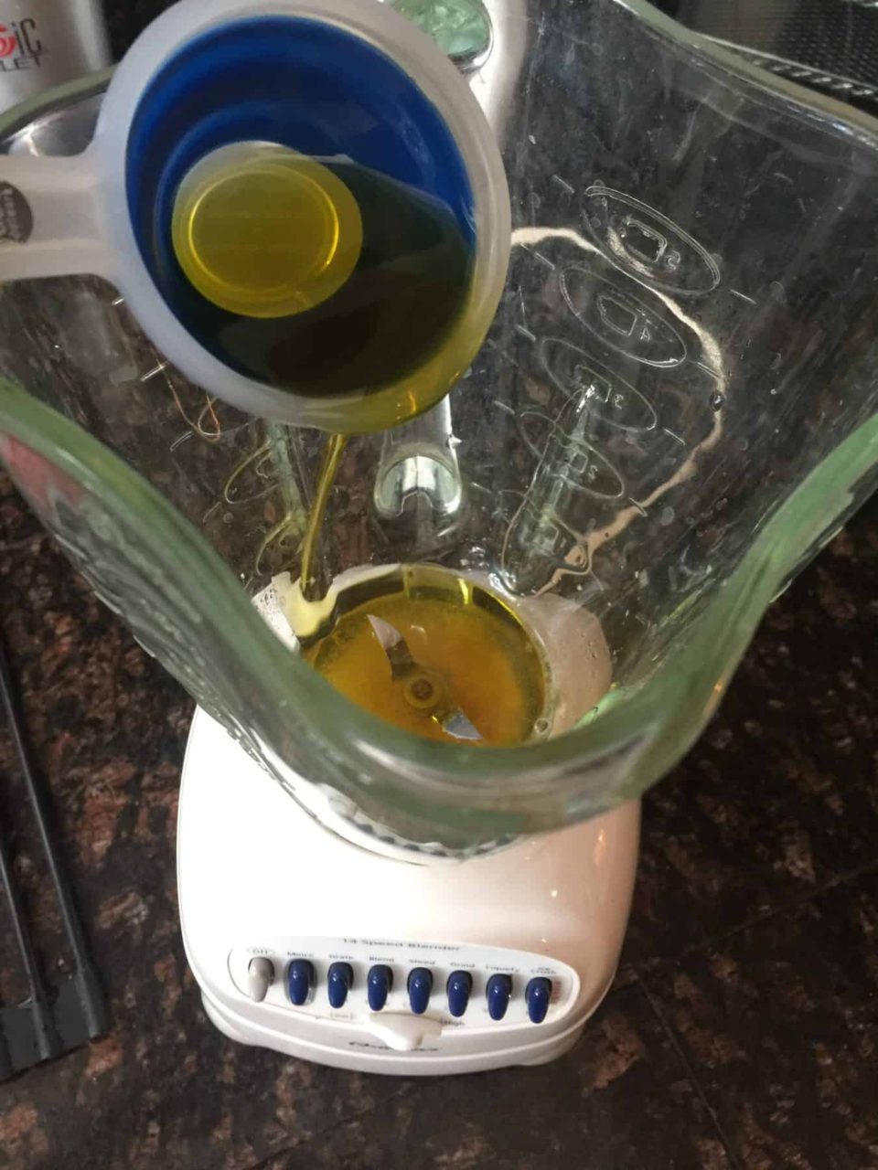 Blender with olive oil being added.