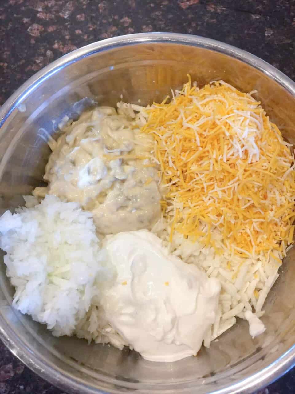 Potatoes, cheese, onion, sour cream and soup in a bowl prior to mixing.