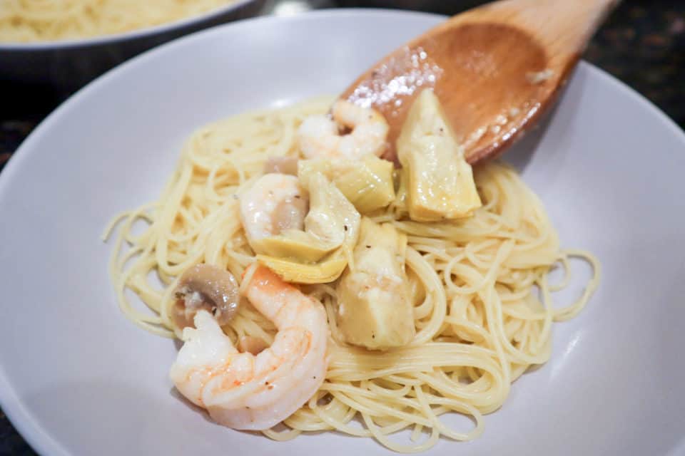 Spooning shrimp mixture over the pasta for Weeknight Shrimp Portofino.