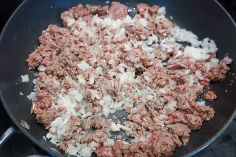 Ground beef and onions frying in a skillet for Oven Baked Taco Casserole.