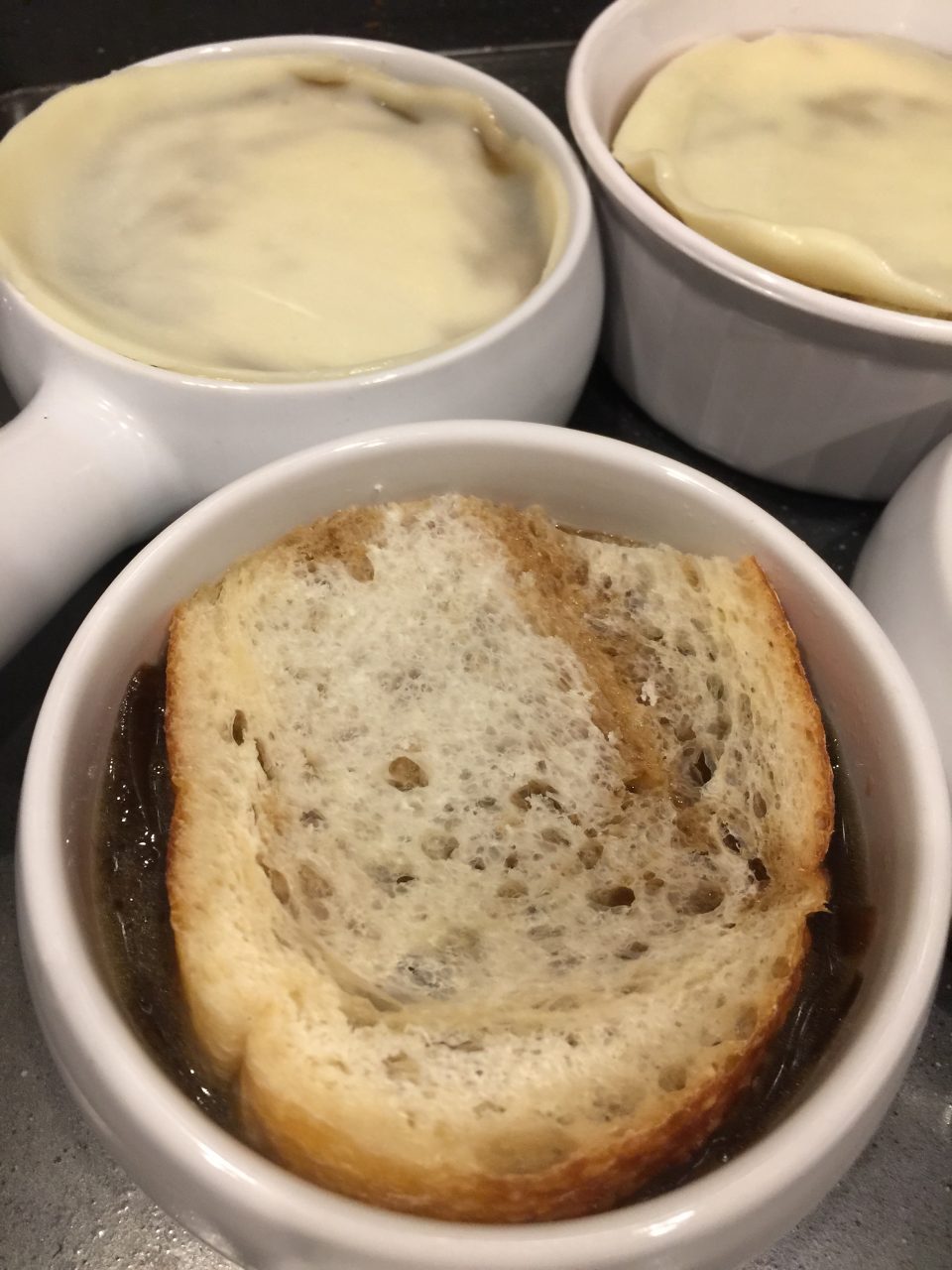Adding bread & cheese to French onion Soup bowls before broiling.