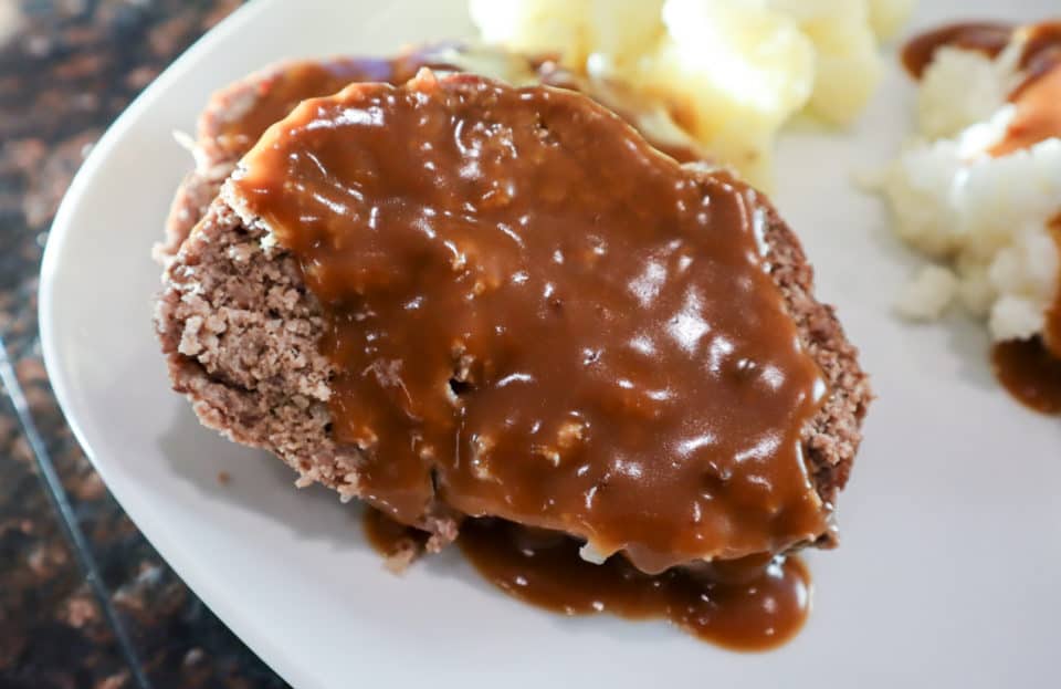 Finished Simple Weeknight Meatloaf on a plate with gravy.