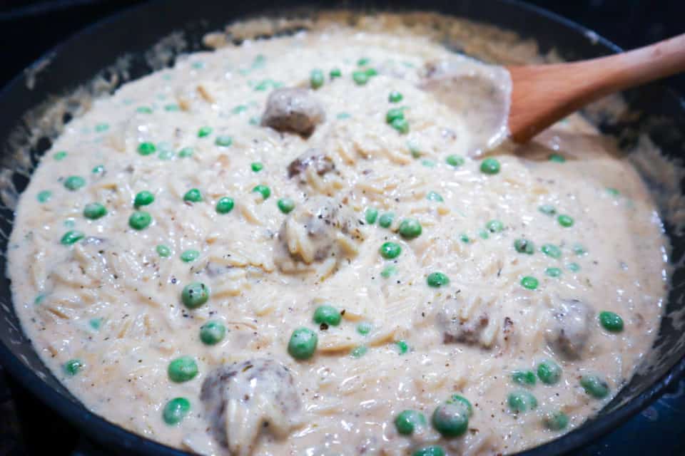 Creamy Orzo with Meatballs and Peas stirred together in the skillet just before serving.