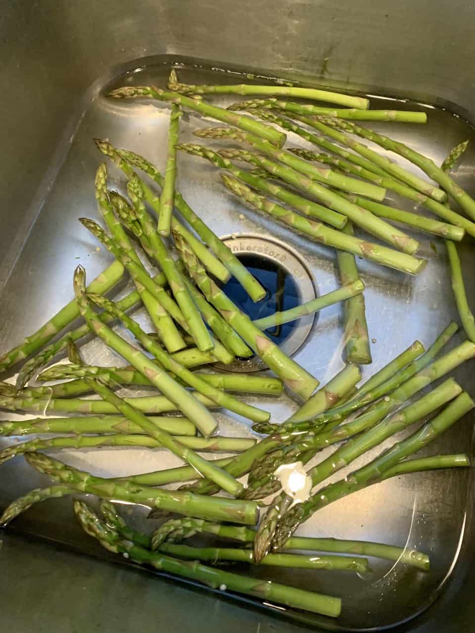Asparagus getting rinsed in the sink