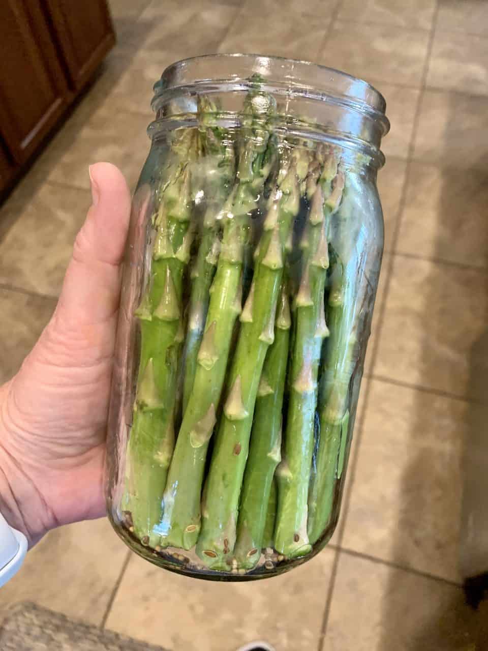 Asparagus getting put into a quart mason jar