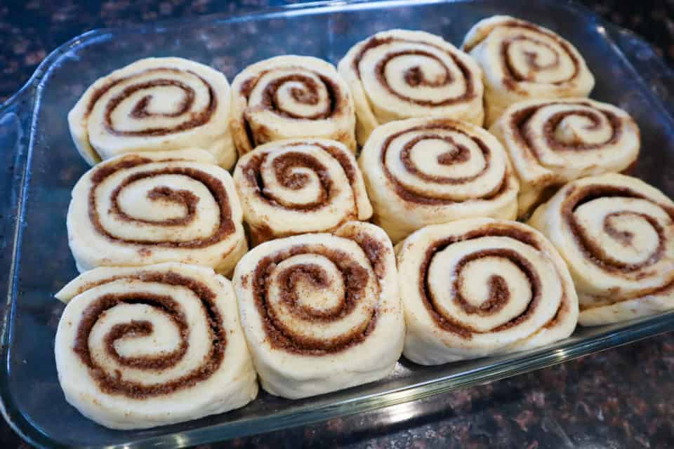 Homemade Cinnamon Buns in a glass baking dish, after rising, before baking.