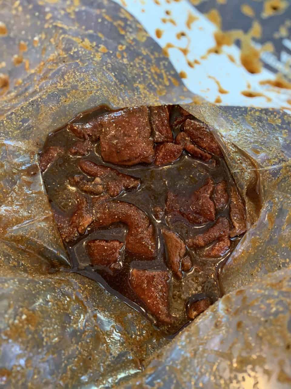 Beef strips in marinade in a zip top bag.
