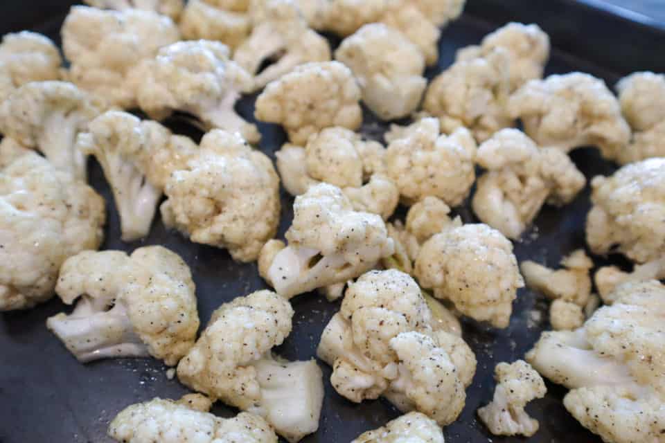 Picture of coated cauliflower on a baking sheet ready to be put into the oven. 