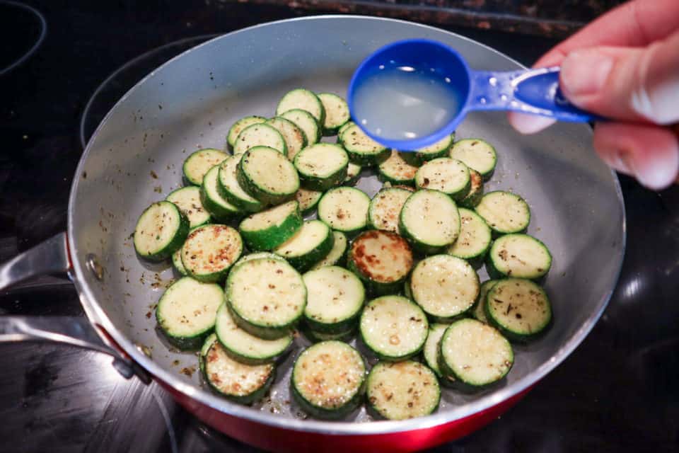 Picture of lemon juice being added to zucchini in the skillet for Simple Sauteed Zucchini with Lemon.
