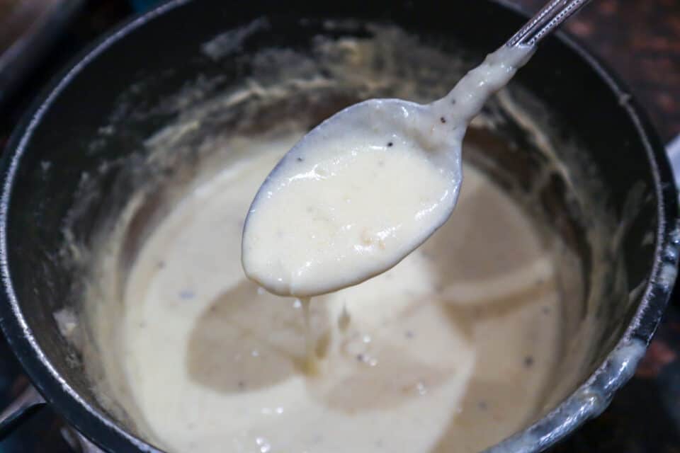 Thickened 4 Ingredient Alfredo Sauce on a spoon.
