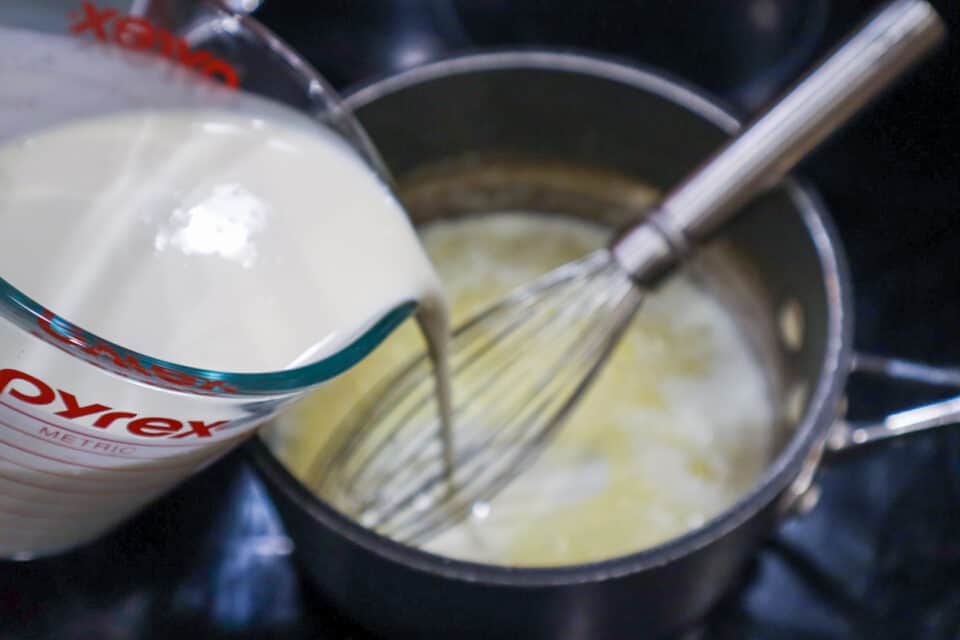 Adding heavy cream to the saucepan.