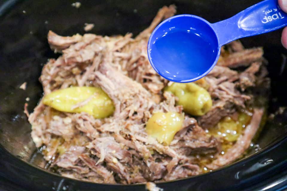 Pepperoncini juice being added to shredded Mississippi Pot Roast