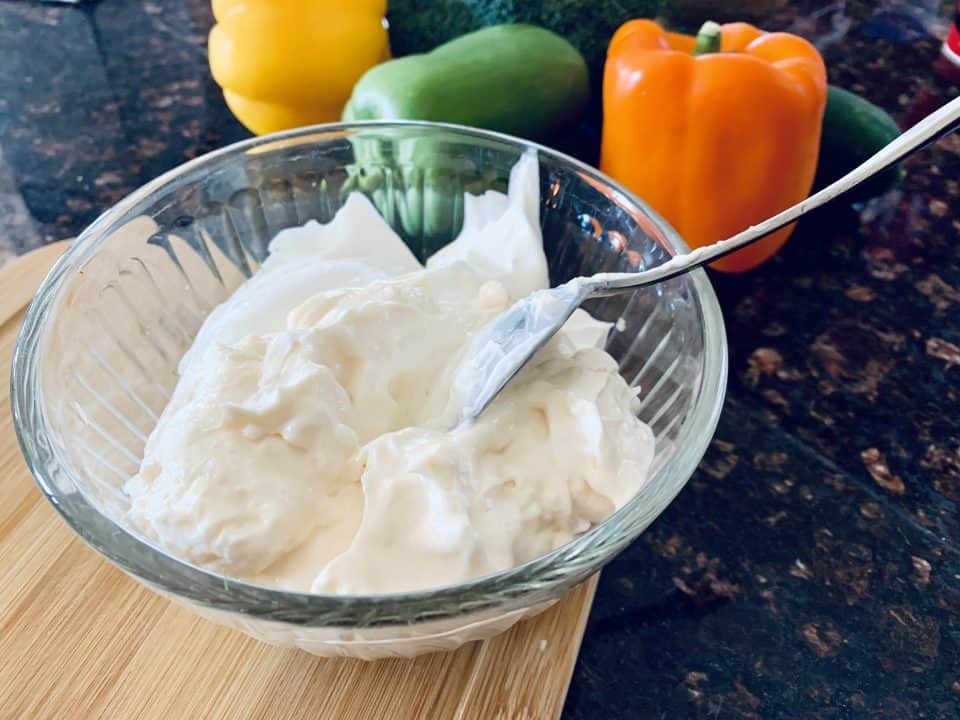 Mayonnaise and sour cream being added to the spices in the bowl for Easy Homemade Ranch Dip.