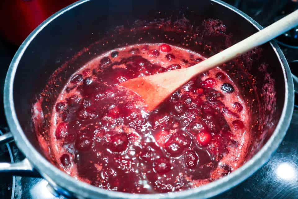 Simple Homemade Cranberry Sauce in a saucepan with a wooden spoon.