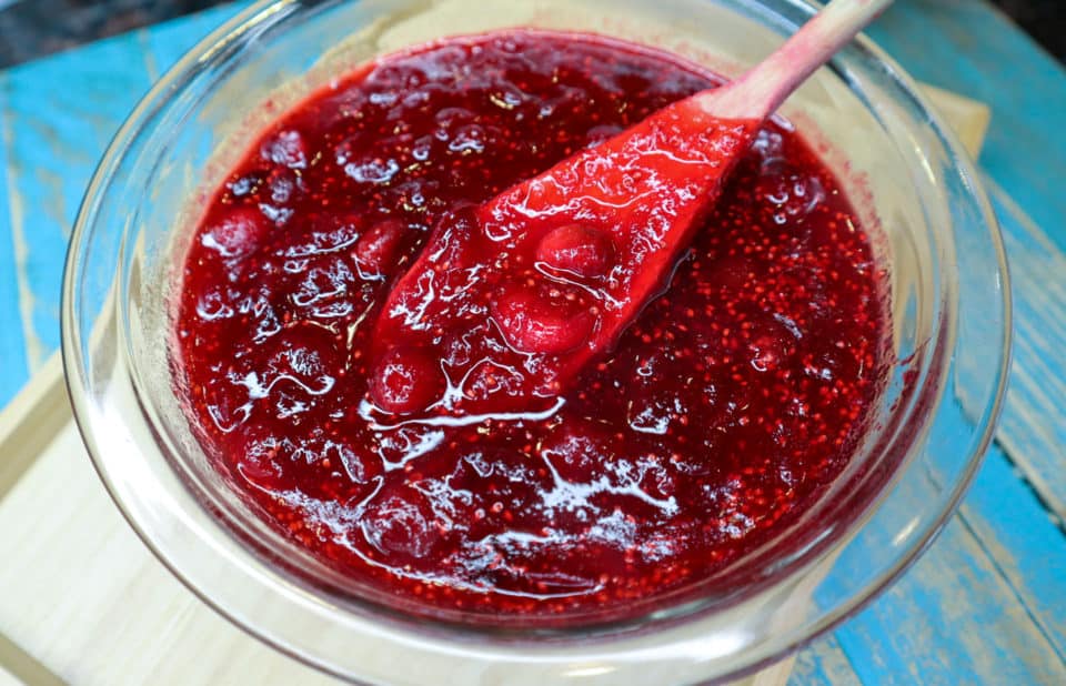 Finished Simple Homemade Cranberry Sauce in a bowl with a wooden spoon.