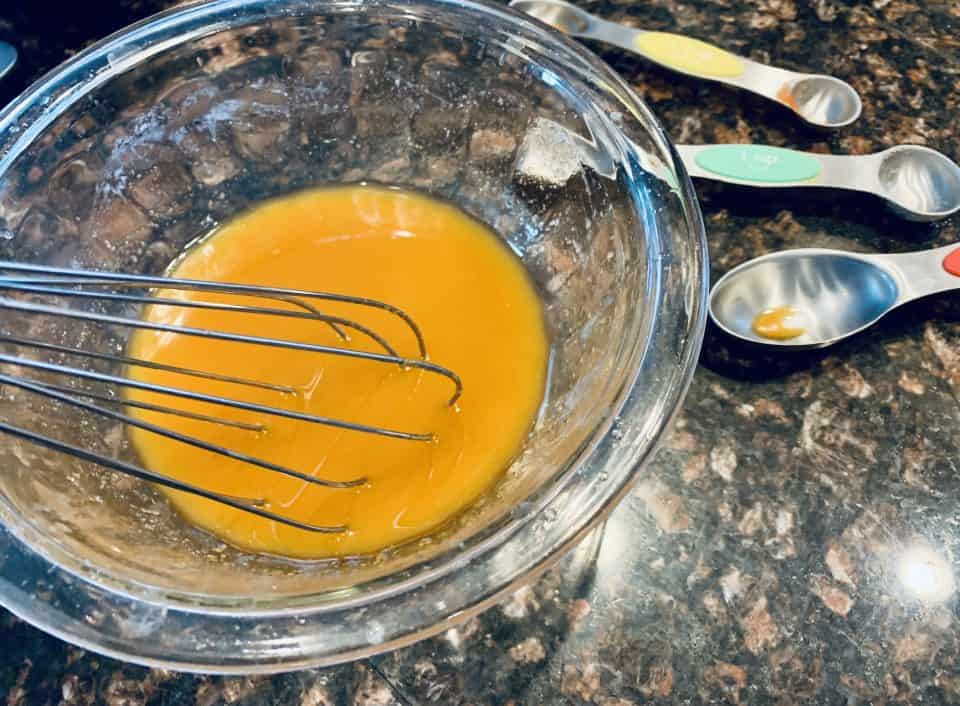 Melted butter and seasonings being whisked together for Savory Chex Mix.