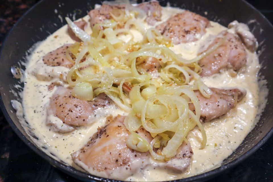 Picture of chicken thighs and onions in cream sauce in the skillet