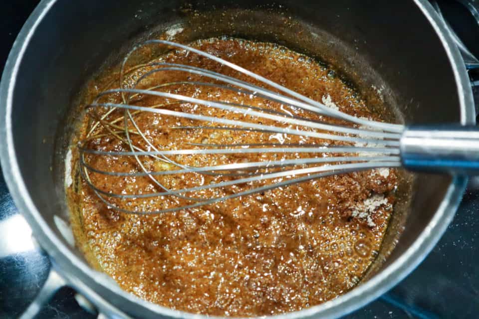 Picture of dry ingredients being whisked into oil in saucepan for Homemade Red Enchilada Sauce.
