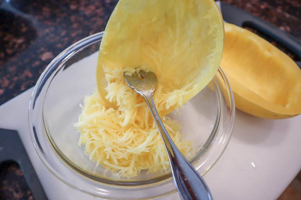 Cooked Spaghetti Squash being shredded with a fork for Garlic Parm Spaghetti Squash.