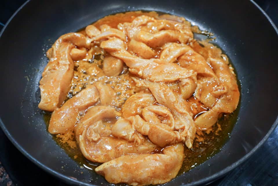Picture of marinated chicken strips being fried in a skillet for One Pan Chicken Fajitas.