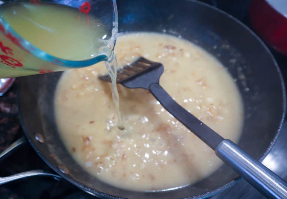 Picture of broth being poured into skillet mixture for Easy Pork Chops with Pan Sauce.