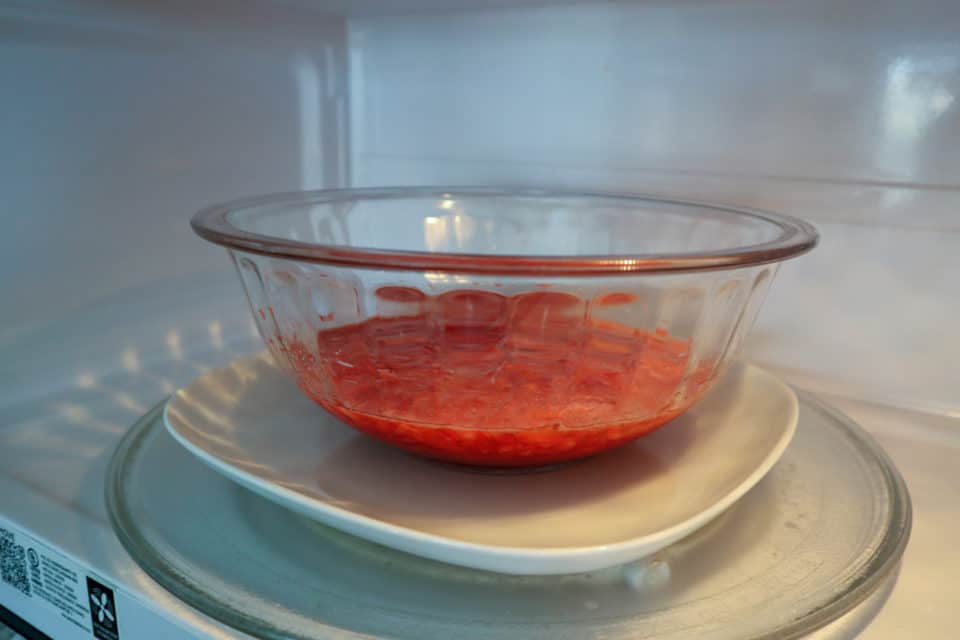 Picture of pre-cooked Simple Microwave Strawberry Jam in a bowl, on a plate, in the microwave.