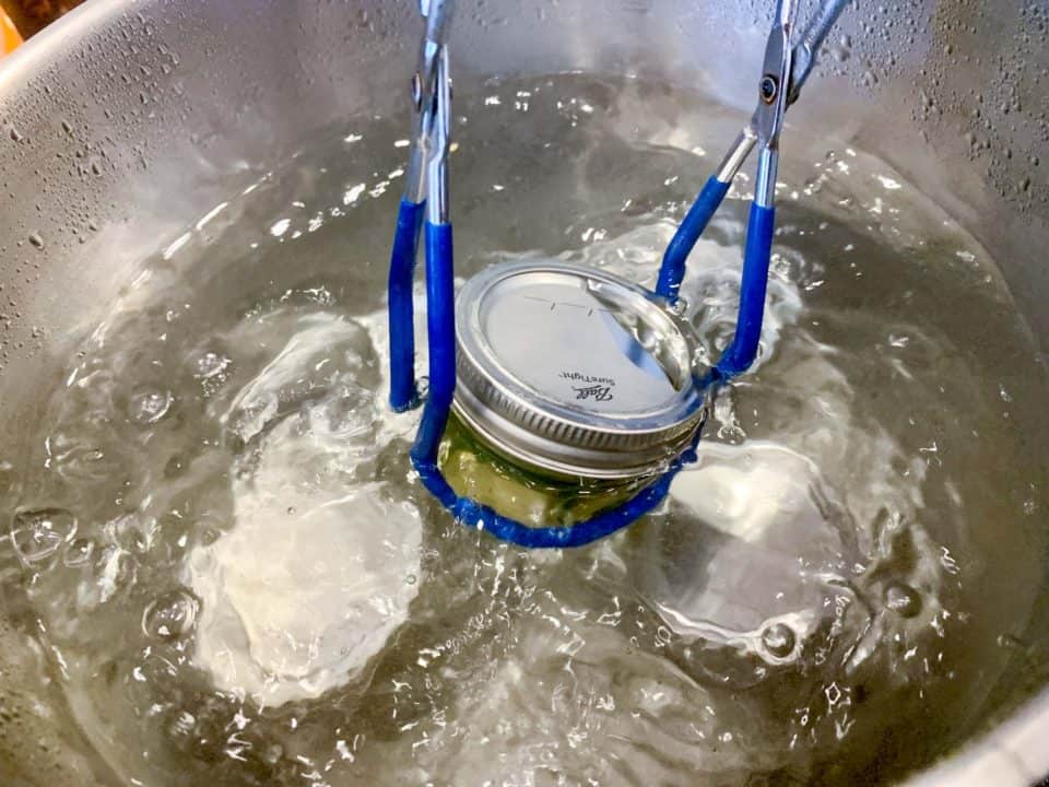 Picture of jars of Pineapple Cowboy Candy being placed in a water bath canner.