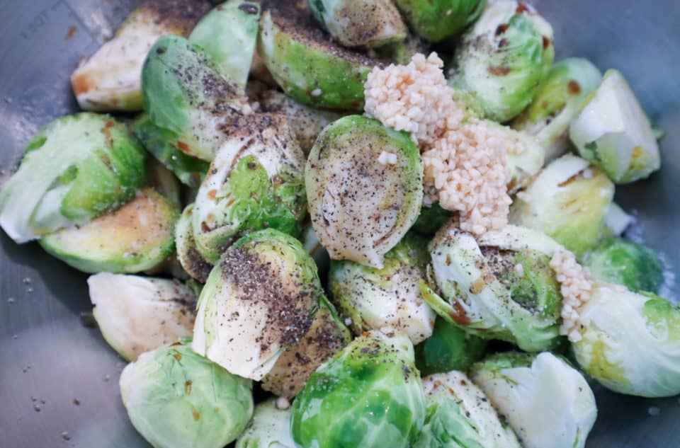 Picture of Brussels sprouts and seasonings (unmixed) in a bowl.