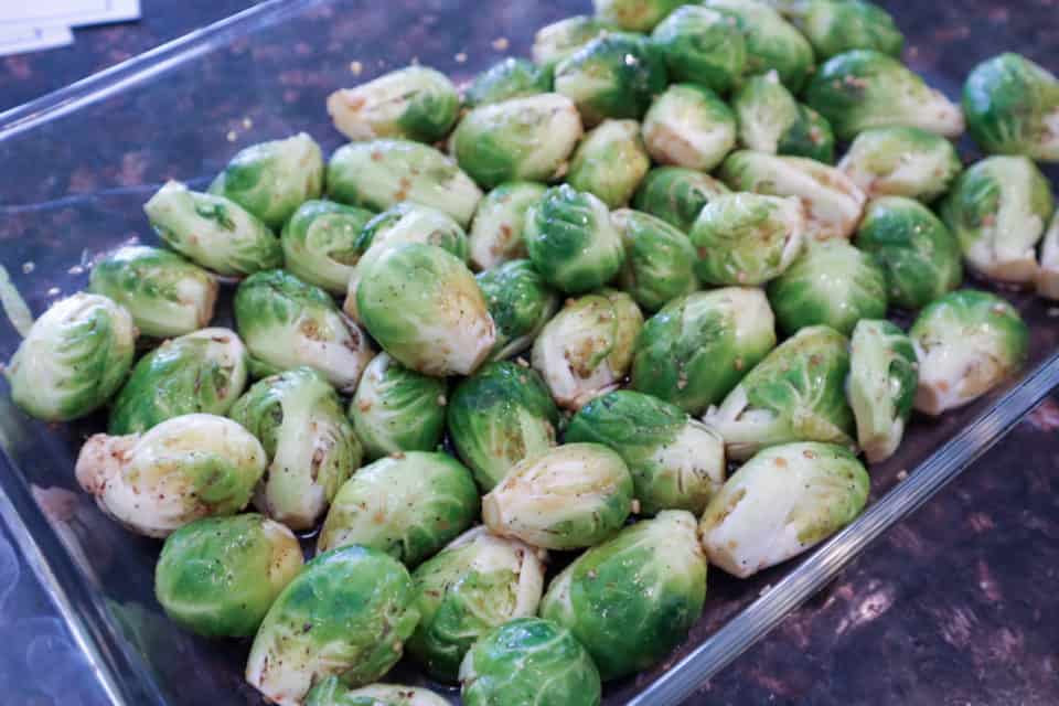 Picture of Brussels sprouts after being tossed in seasonings in a baking dish.