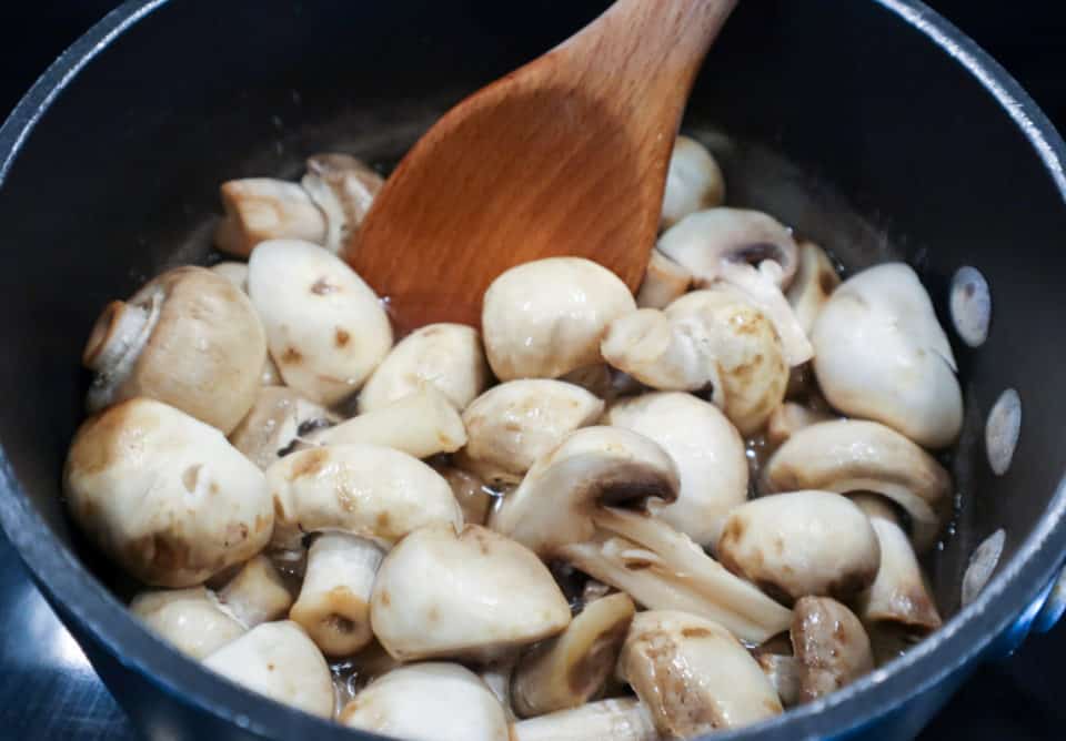 Picture of mushrooms being stirred into vinegar mixture for Easy Italian Pickled Mushrooms.