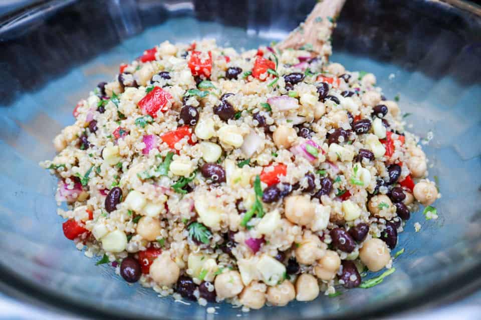Picture of finished Southwestern Quinoa Salad in a bowl with a wooden spoon.