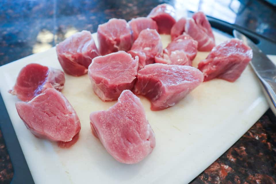 Pork medallions on a cutting board with a knife.