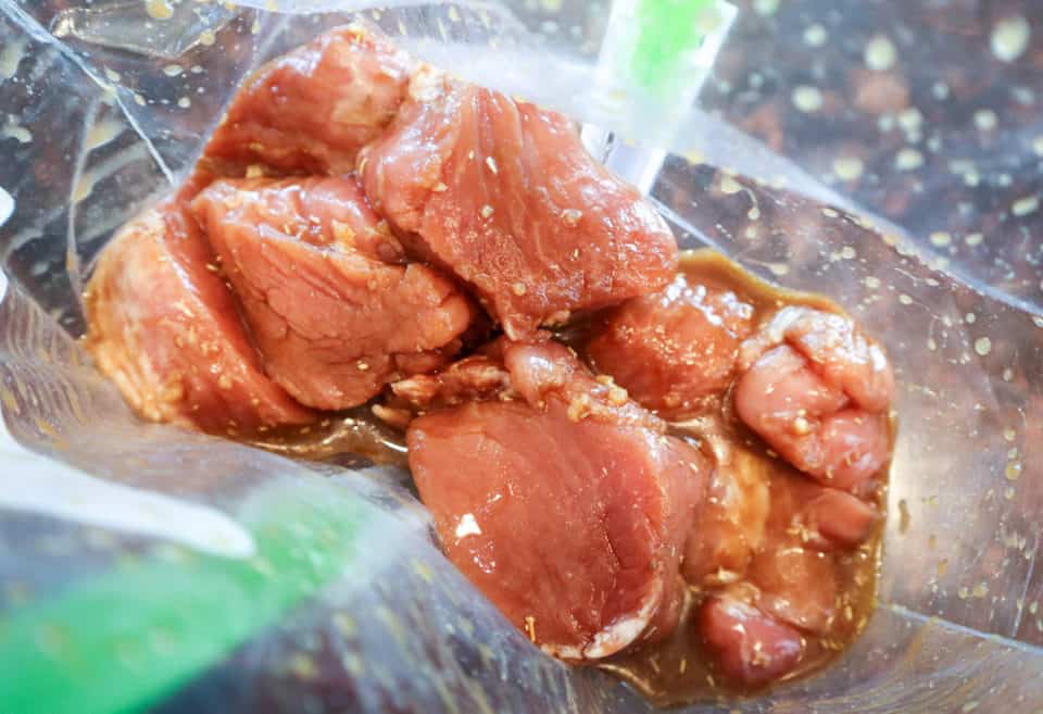 Pork medallions in a zip top bag covered by marinade.