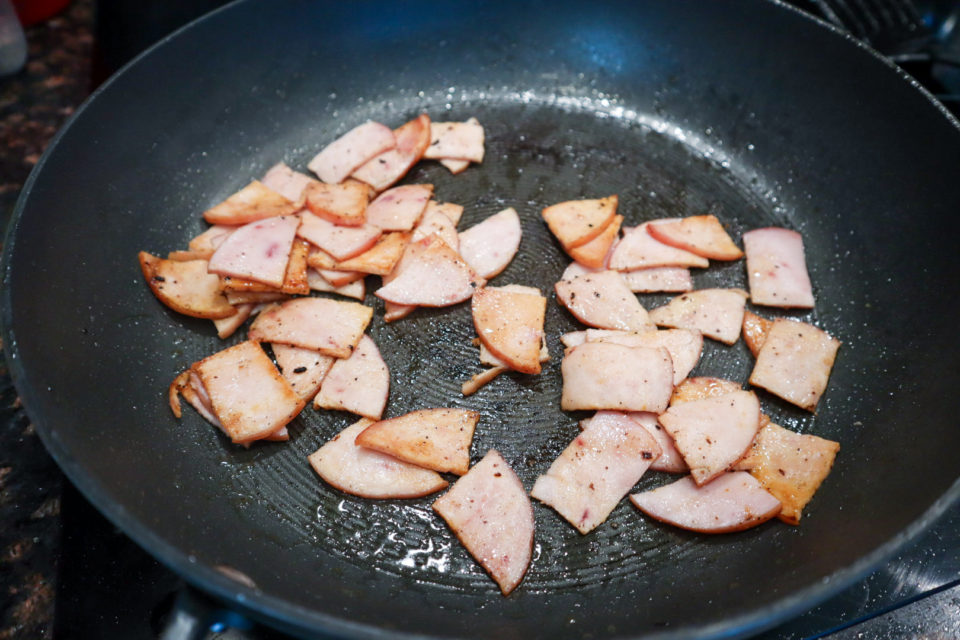 Picture of Canadian Bacon being browned in a skillet for Hearty Baked Breakfast Casserole.