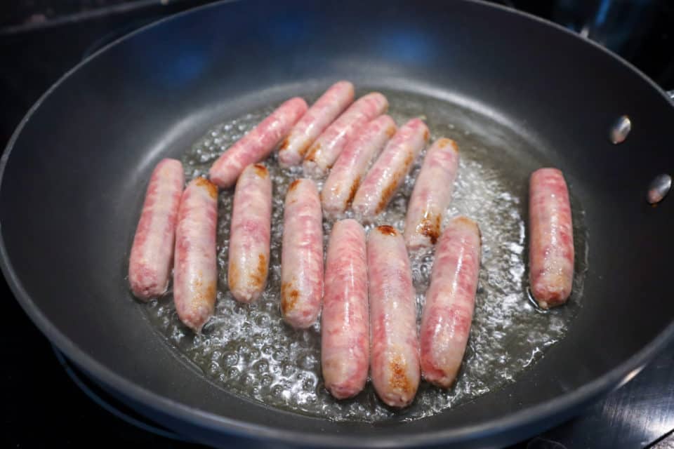 Picture of sausages being browned in a pan for Hearty Baked Breakfast Casserole.
