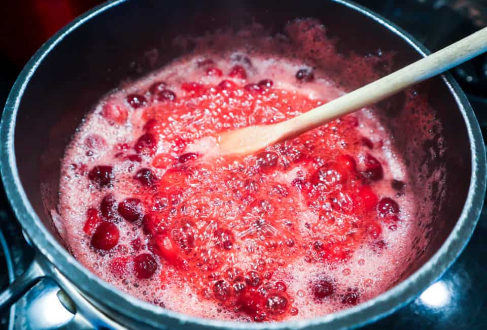 Simple Homemade Cranberry Sauce mixture bubbling in a saucepan.