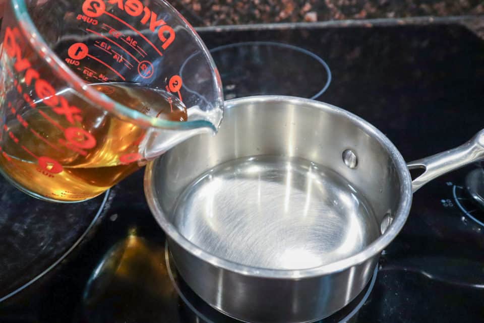 Pouring vinegar into a saucepan with water.